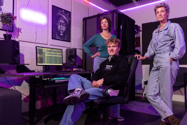 Drie witte mensen, twee vrouwen en een man in een muziekstudio