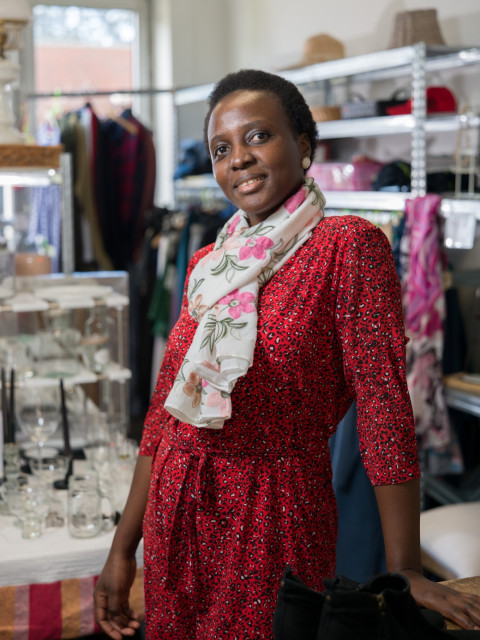 Zwarte vrouw met vrolijke rode jurk en sjaal met bloemen in een winkeltje