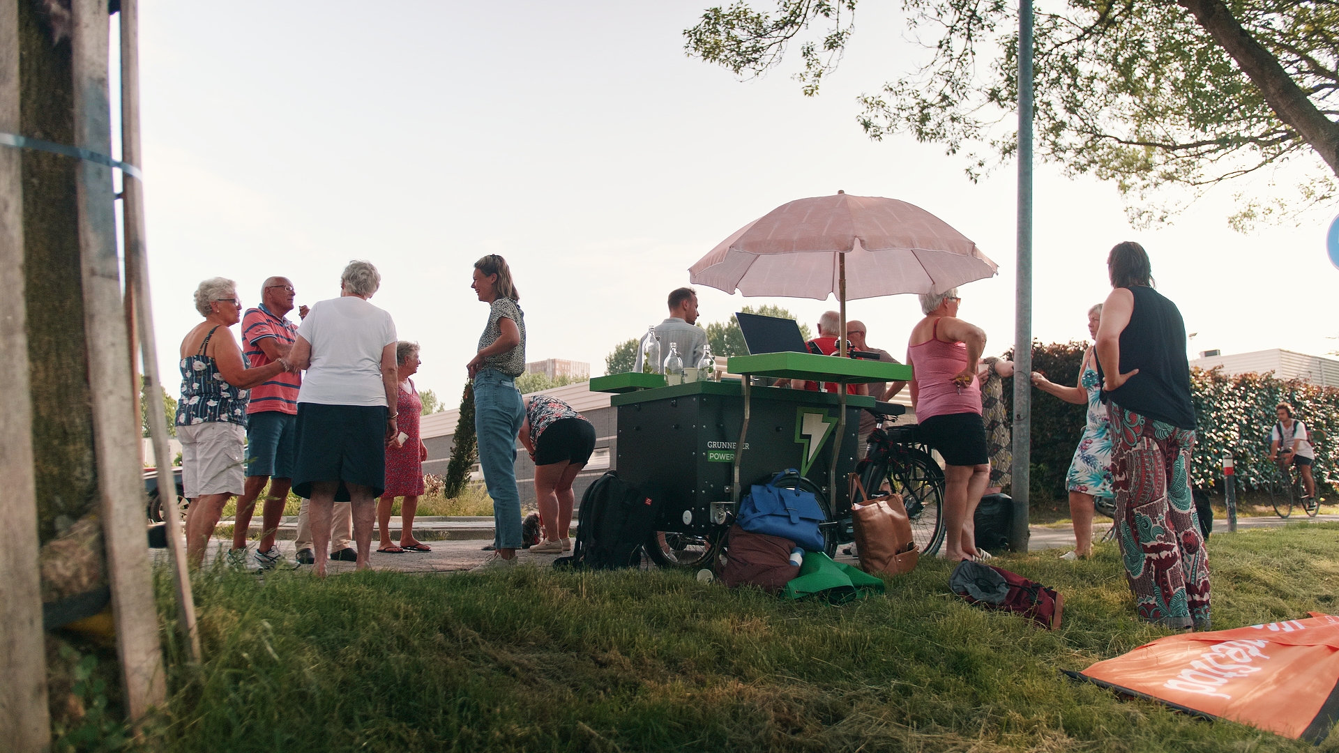 Still uit de aflevering Aanleg warmtenet, waarop een informatiewagentje van Grunneger Power te zien is met daar omheen wijkbewoners