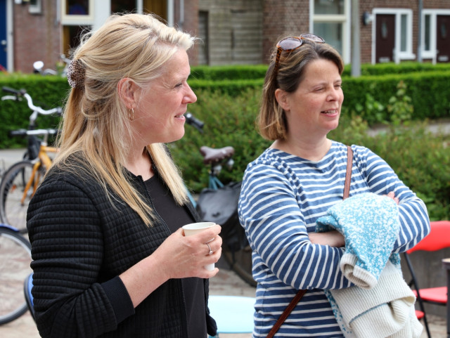 Twee witte vrouwen op een pleintje kijken naar iets buiten beeld