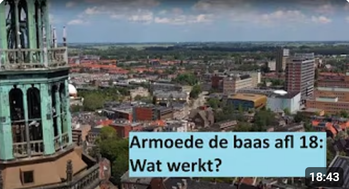 Still uit de aflevering waarop een luchtfoto is te zien van de stad Groningen met links daarop een stukje van de Martinitoren. In beeld staat de tekst Armoede de baas afl 18: Wat werkt?