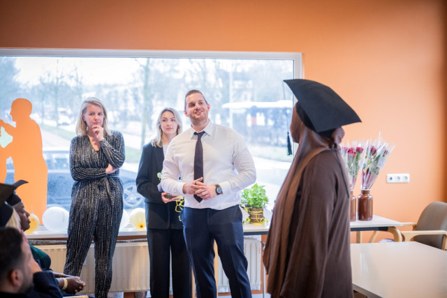 Witte man in pak spreekt trots een vrouw met hoofddoek toe